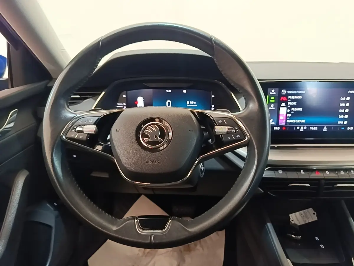 Vue intérieure centrée sur le volant cuir noir de la Skoda Octavia 2024 avec tableau de bord digital et écran tactile.