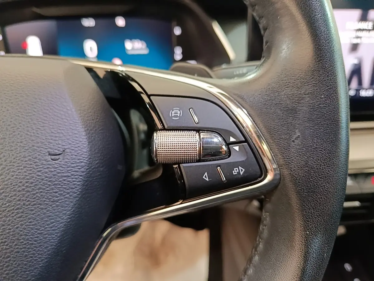 Gros plan sur le volant en cuir noir de la Skoda Octavia 2024, avec commandes multifonctions et molette métallique.