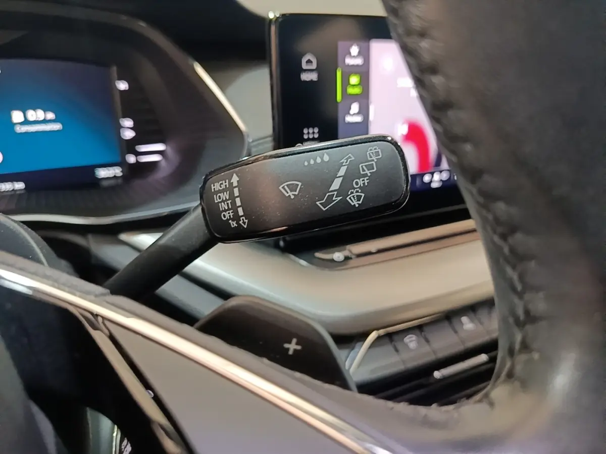 Gros plan sur la manette d’essuie-glace noire côté gauche du volant cuir dans l’habitacle de la Skoda Octavia 2024.