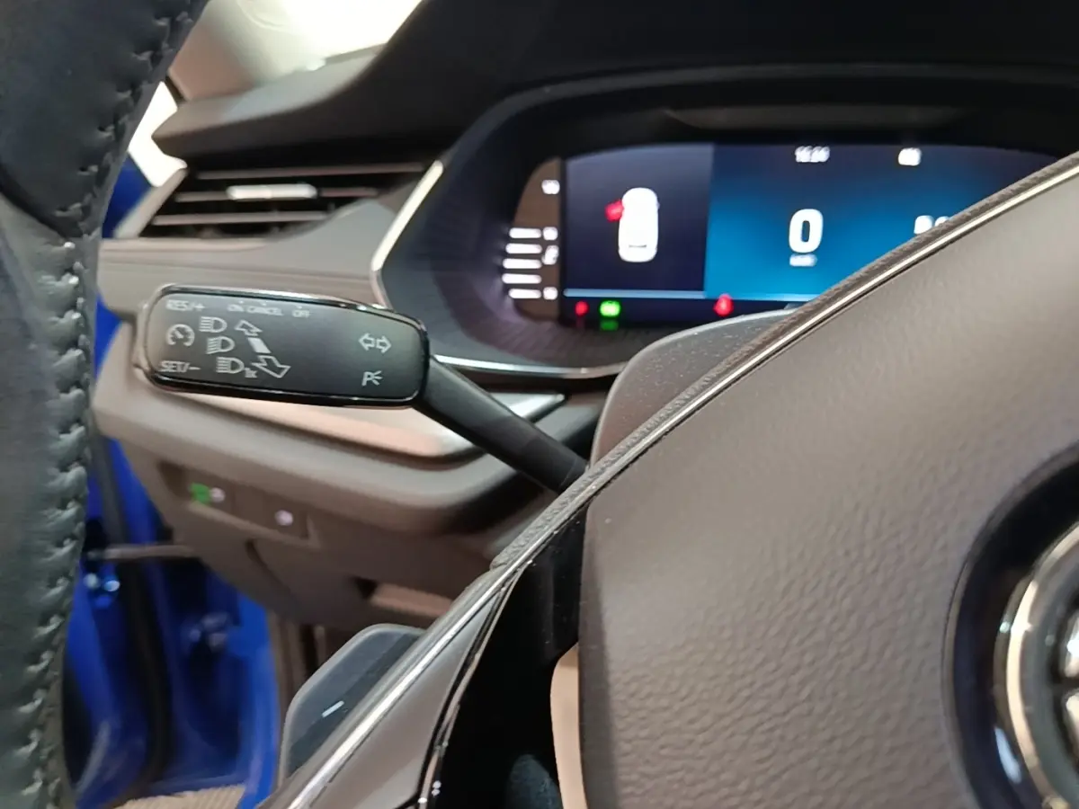 Gros plan sur la commande de régulateur de vitesse à gauche du volant dans l'habitacle bleu d'une Skoda Octavia 2024.