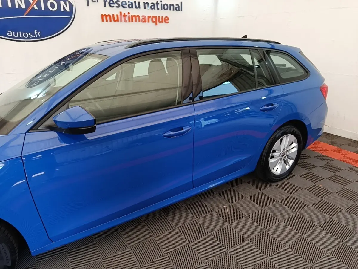Vue latérale droite d'une Skoda Octavia break 2024 bleu vif avec rétroviseurs électriques et jantes alliage.
