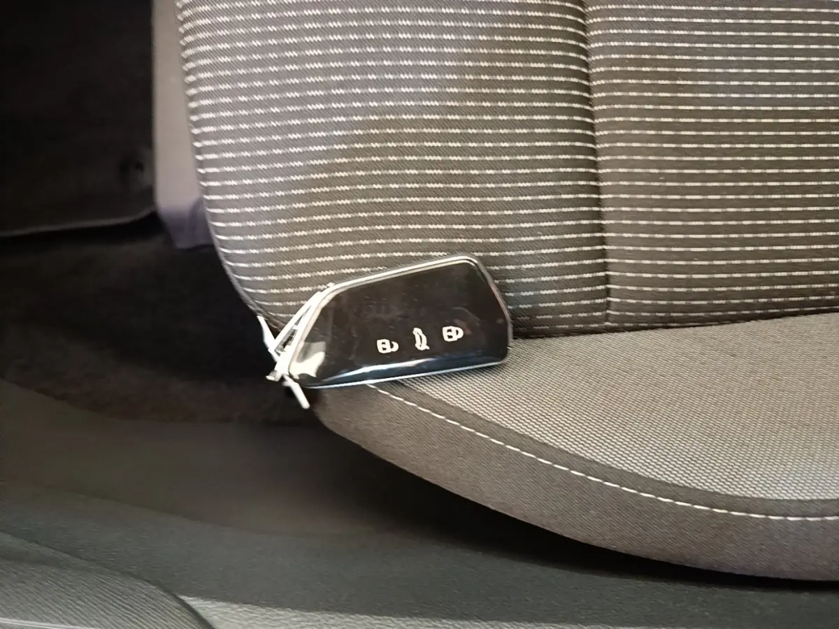 Clé de voiture noire posée sur le siège avant gris à motifs rayés de la Skoda Octavia 2024.