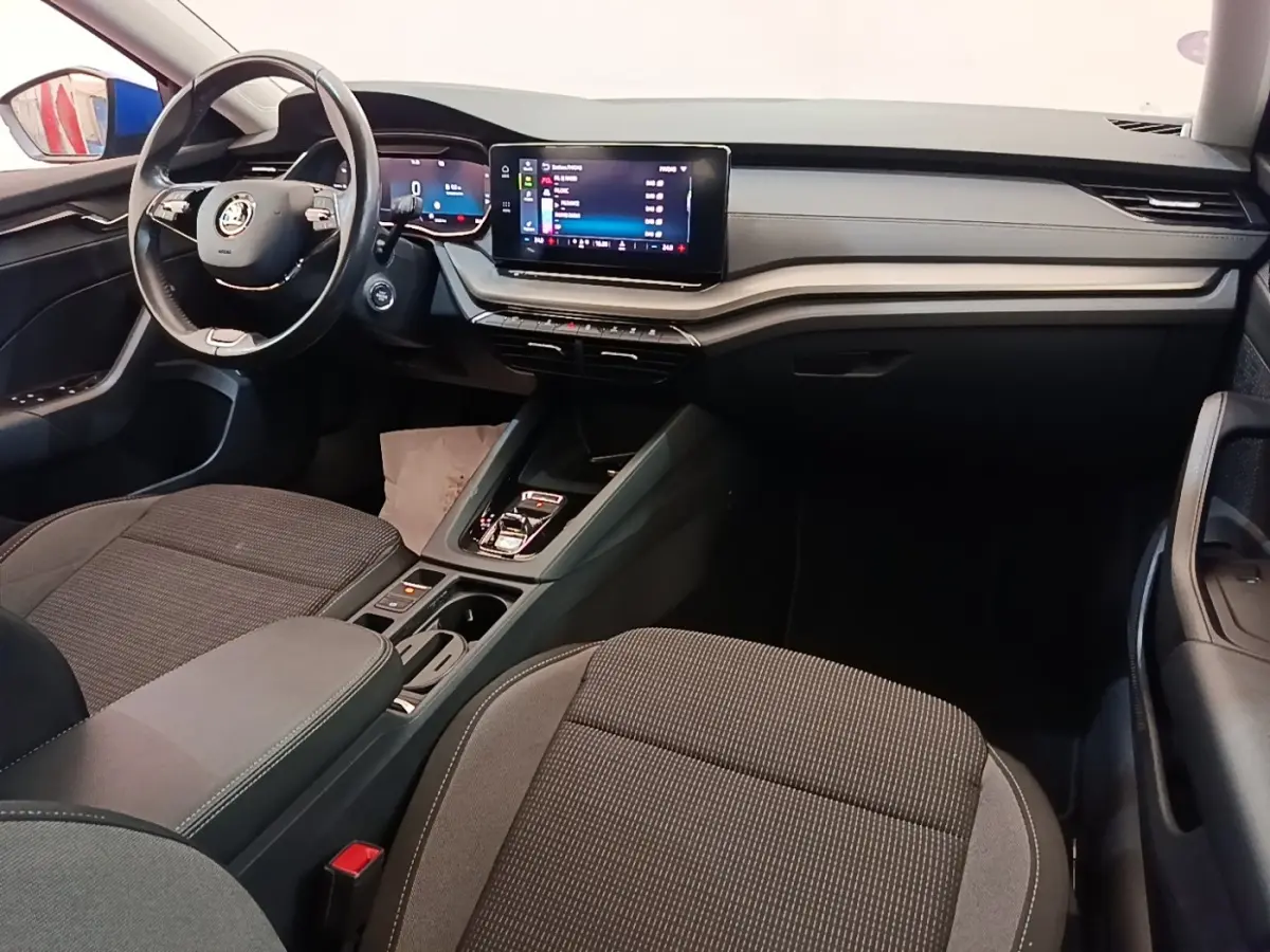 Vue intérieure côté conducteur de la Skoda Octavia 2024, tableau de bord noir avec écran tactile central et volant cuir.