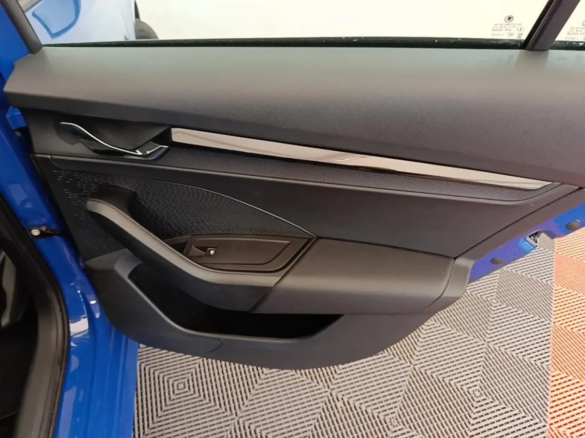 Vue intérieure de la porte côté gauche d’une Skoda Octavia 2024 bleue avec garniture noire et insert chromé.