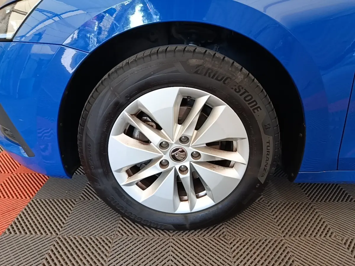 Gros plan sur la roue avant gauche d'une Skoda Octavia bleue, avec jante argentée et pneu Bridgestone.