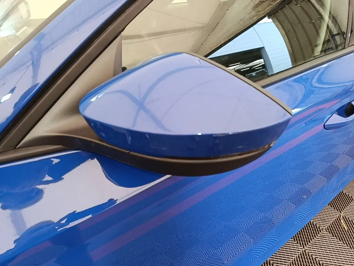 Gros plan sur le rétroviseur côté conducteur bleu d’une Skoda Octavia 2024, avec reflet de la carrosserie bleue.