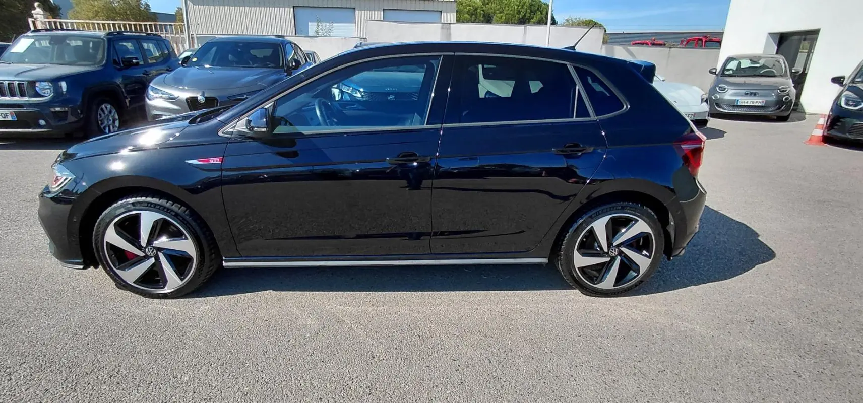 Volkswagen Polo GTI noire vue de profil côté gauche, avec jantes alliage 17 pouces et badge GTI rouge.