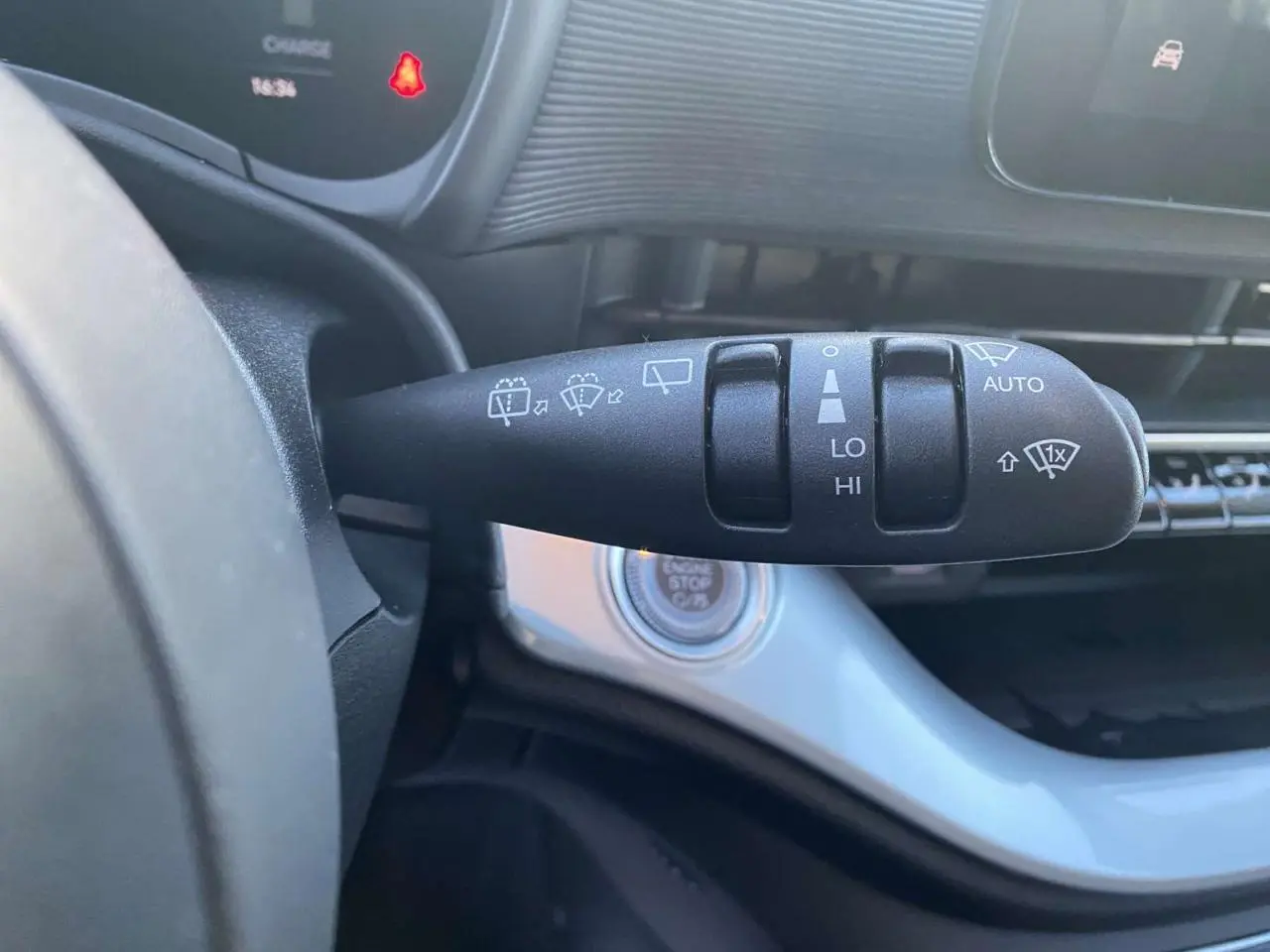 Gros plan sur la commande des essuie-glaces à gauche du volant dans l'habitacle noir de la Fiat 500 électrique 2022.