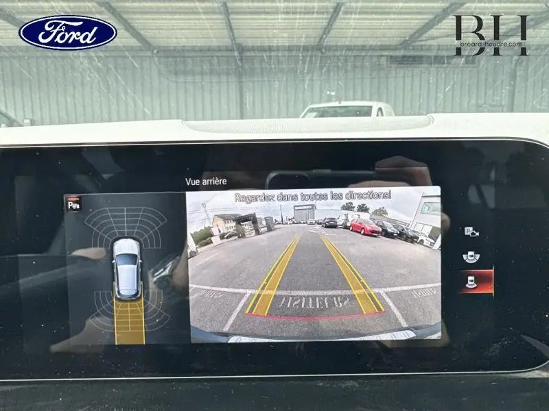 Vue arrière caméra de recul d'un Mercedes GLA bleu denim métallisé, avec lignes de guidage jaunes visibles.