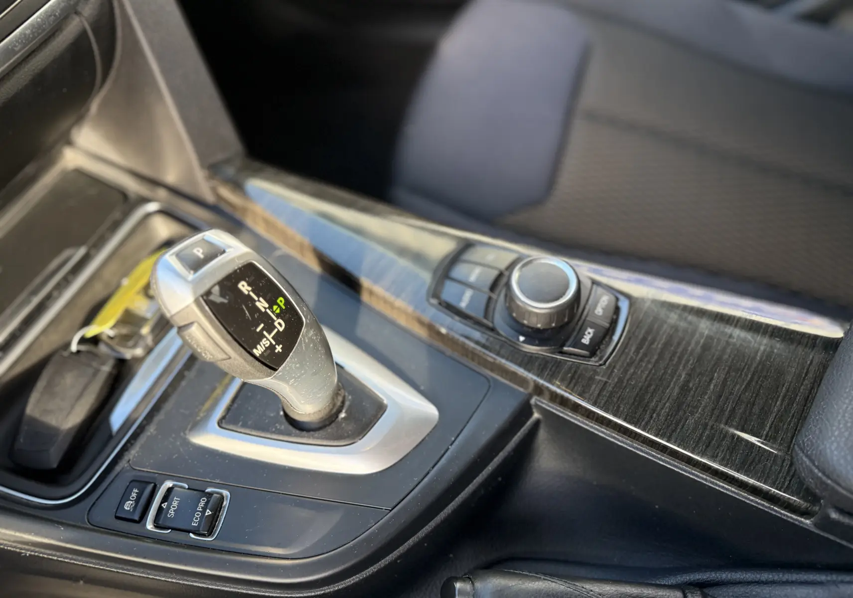 Gros plan sur le levier de vitesses automatique et la console centrale en finition bois sombre d'une BMW Série 3 320D gris.