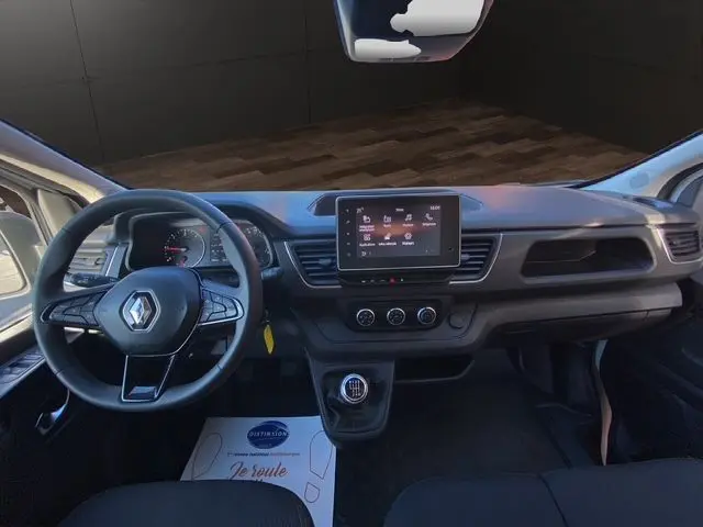 Vue intérieure frontale du tableau de bord du Renault Trafic Fourgon blanc 2023 avec écran tactile et boîte manuelle.