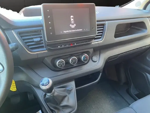 Vue intérieure du tableau de bord du Renault Trafic Fourgon blanc 2023, avec écran tactile et boîte manuelle visible.