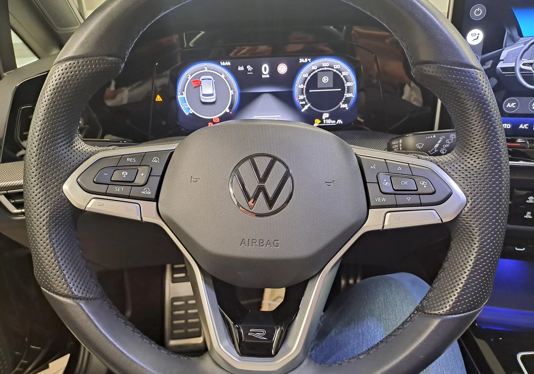 Vue rapprochée du volant perforé noir avec logo Volkswagen et tableau de bord numérique de la Golf 2.0 TDI 2024.