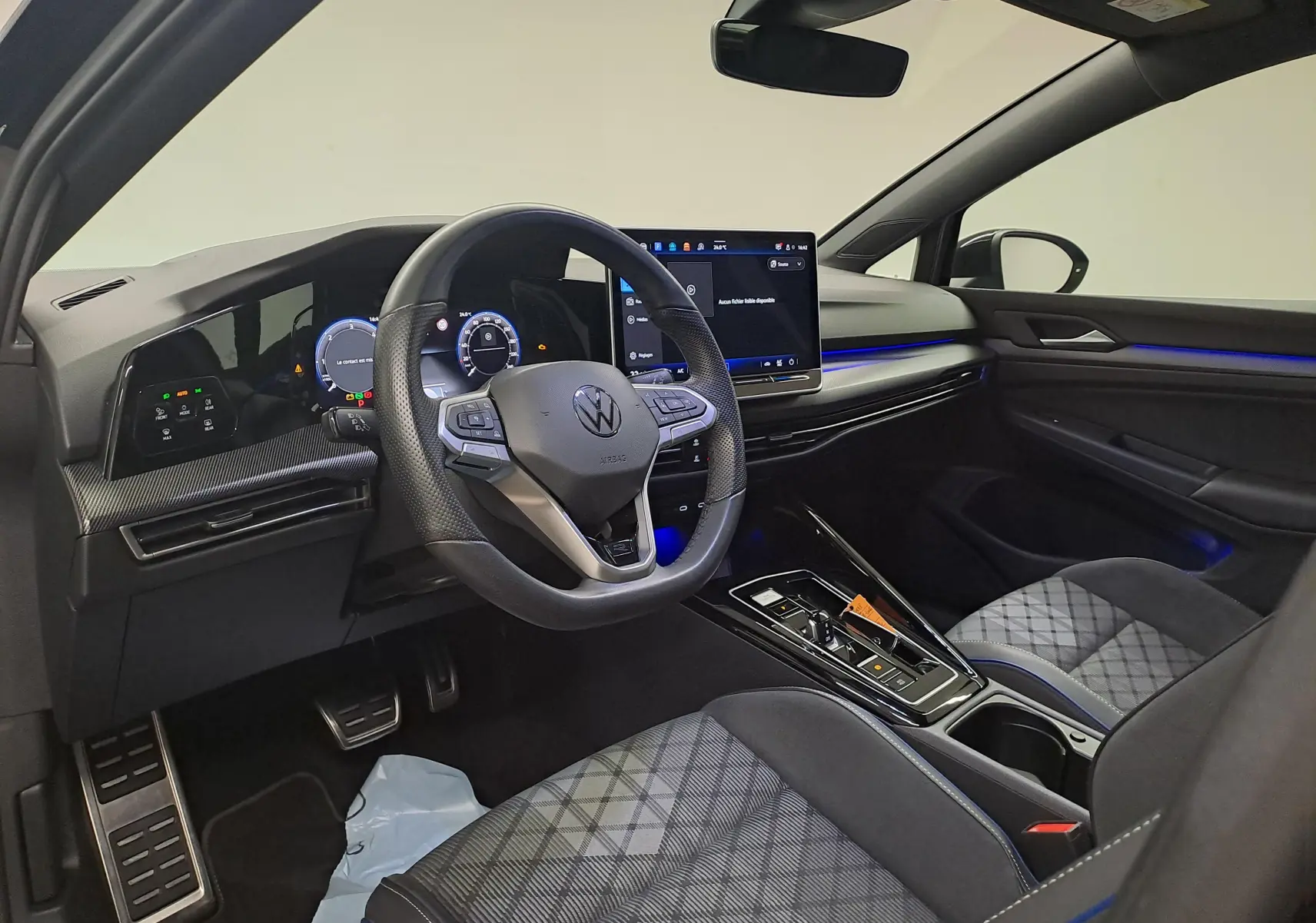 Intérieur côté conducteur de la Volkswagen Golf 2.0 TDI 150 DSG7 R Line 2024 avec éclairage bleu et sièges tissu à motif.