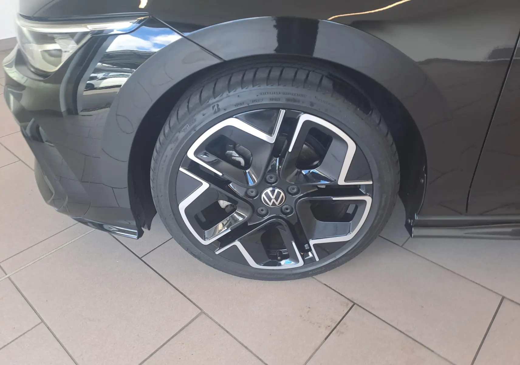 Gros plan sur la roue avant gauche noire grenadille d'une Volkswagen Golf 2.0 TDI 150 DSG7 R Line avec jante alliage 18'' York.