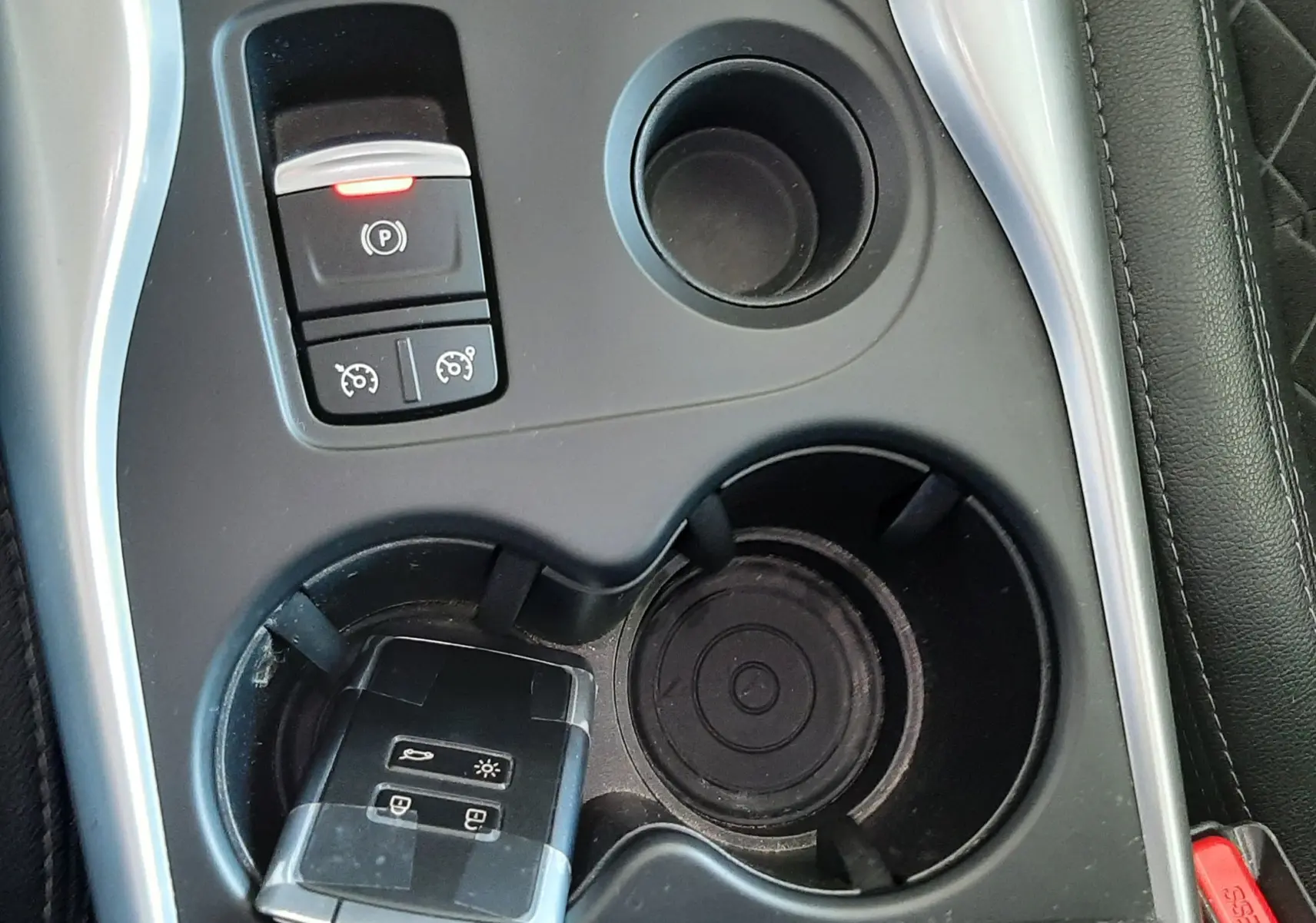 Gros plan sur la console centrale du Renault Kadjar 2020 bleu Iron, avec porte-clés, frein à main électrique et sièges en cuir noir.