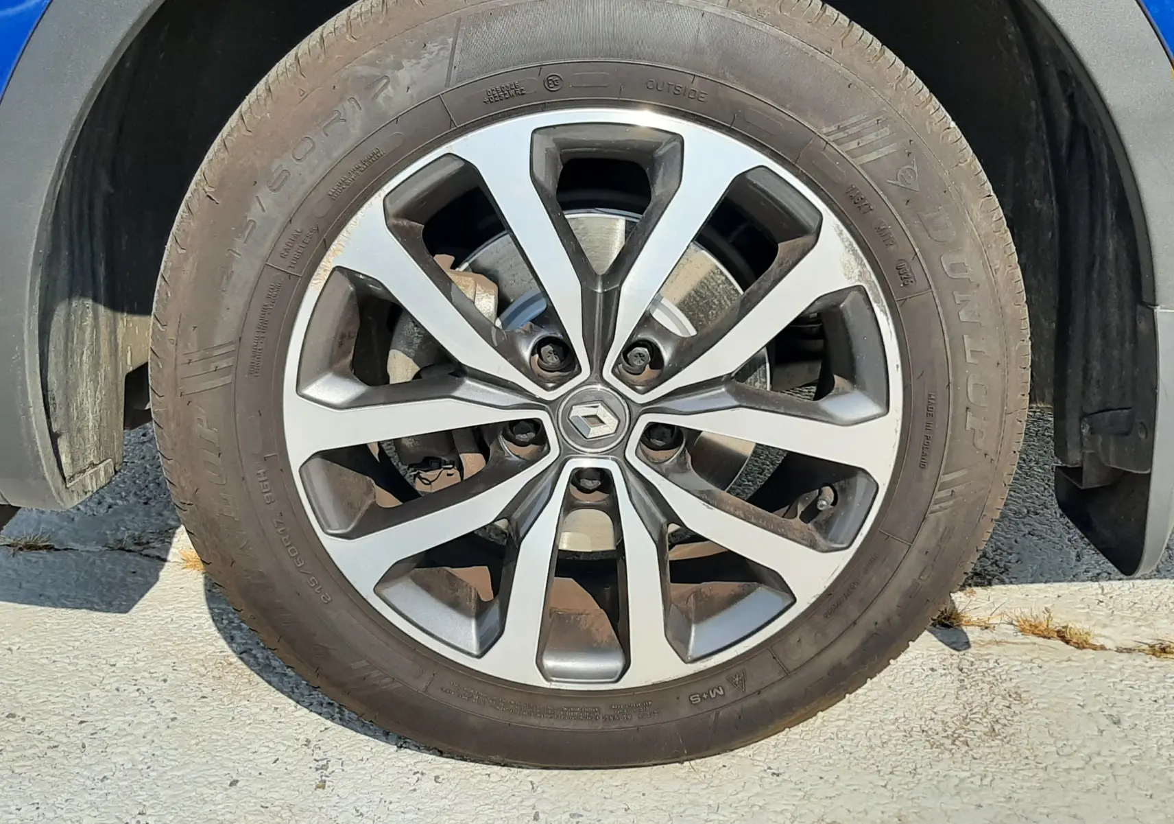 Gros plan sur la roue avant gauche d’un Renault Kadjar bleu iron 2020 avec jante alliage distinctive.