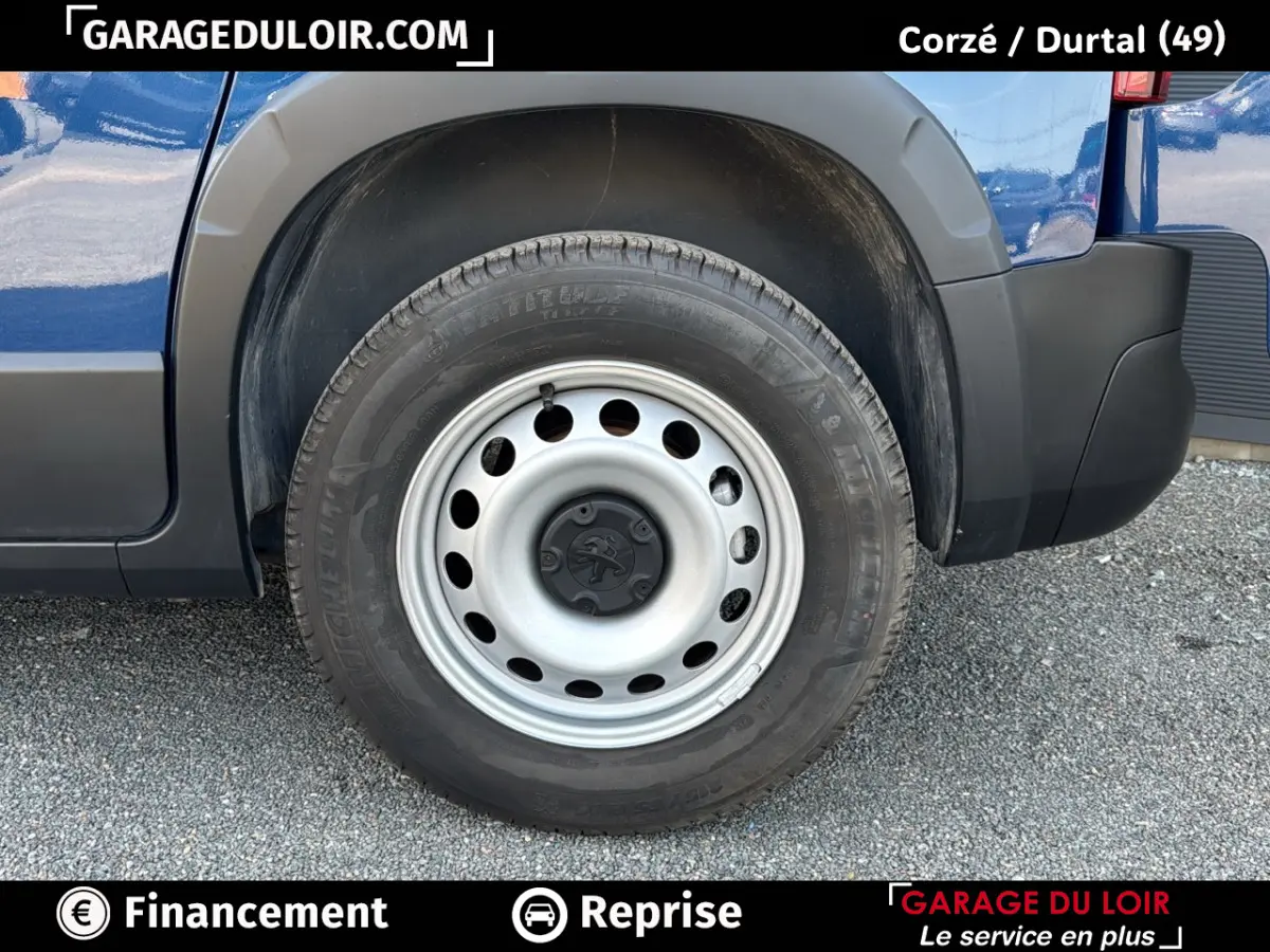 Gros plan sur la roue arrière droite du Peugeot Rifter bleu 2024 avec jante acier et logo Peugeot au centre.