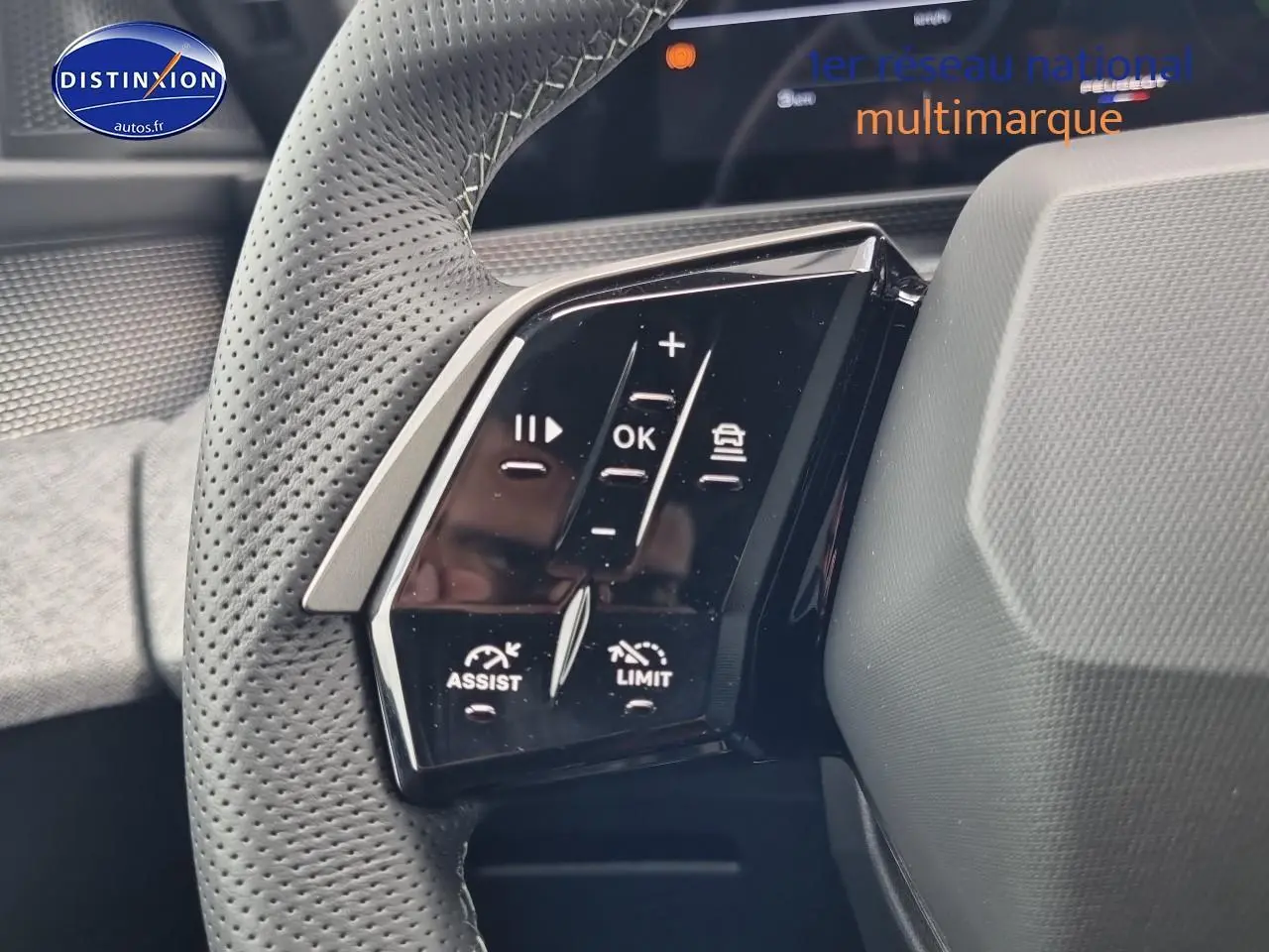 Gros plan sur les commandes noires du volant cuir perforé côté gauche du Peugeot 3008 blanc hybride 2025.