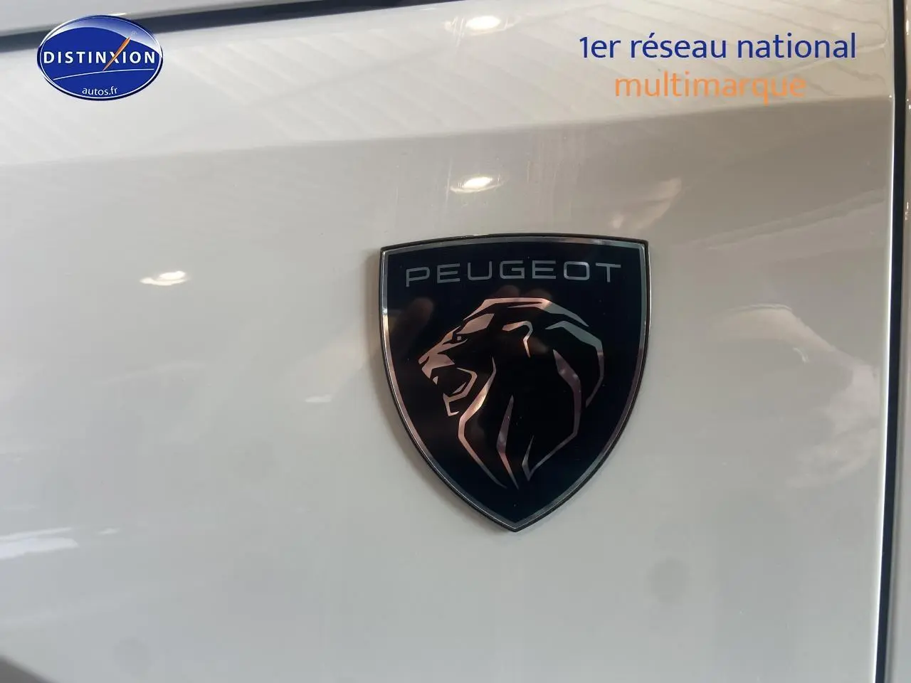Gros plan sur le logo Peugeot noir et argent sur la carrosserie blanche brillante du SUV 3008 hybride.