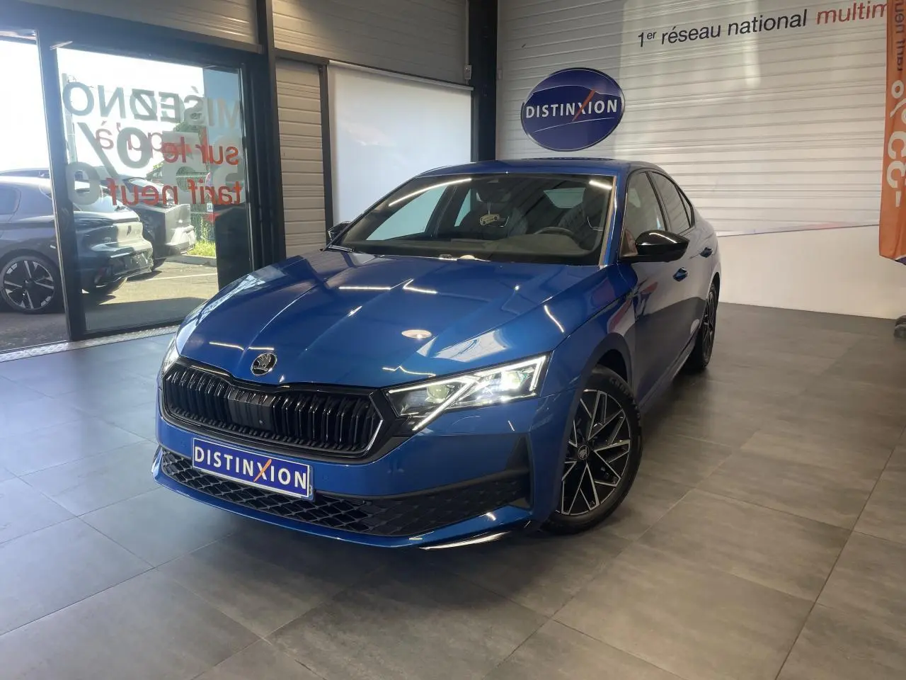 Skoda Octavia 2025 bleu foncé vue 3/4 avant en intérieur avec jantes alliage noires et calandre marquée Sportline.