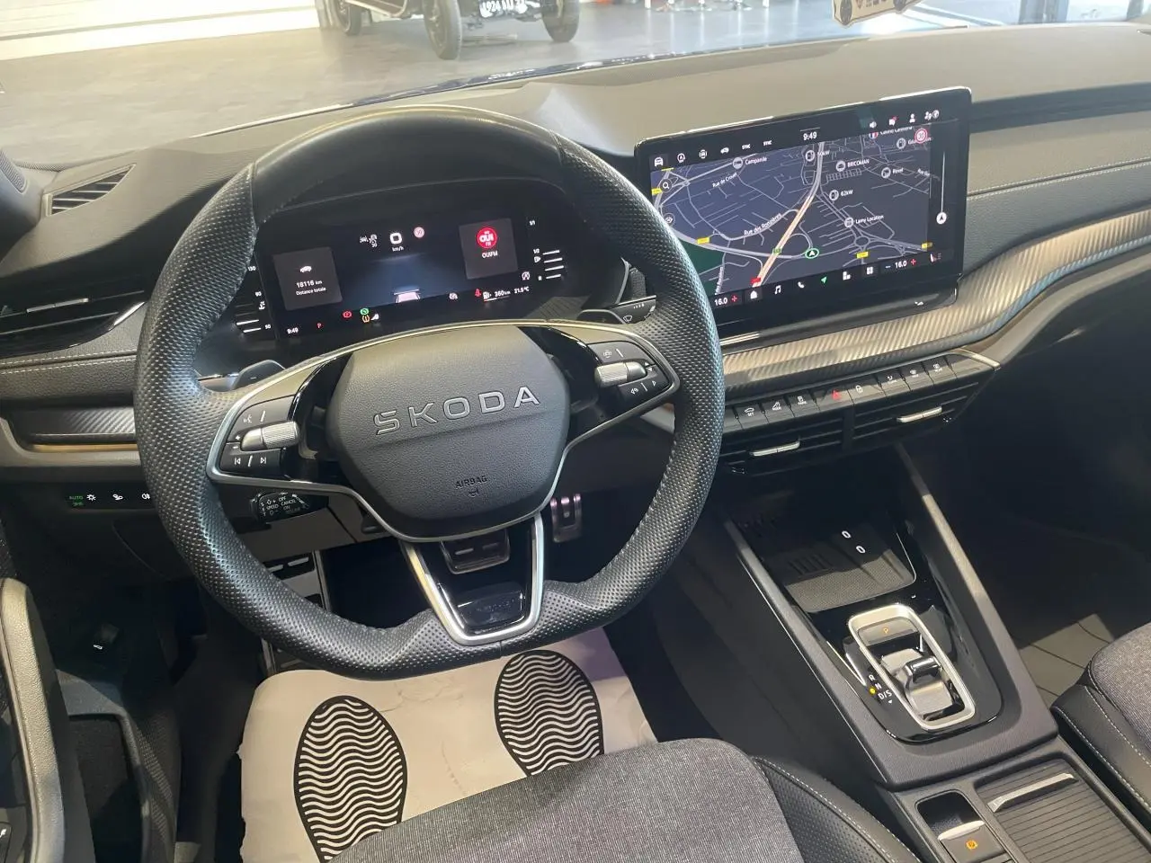 Vue intérieure avant de la Skoda Octavia 2025 bleu foncé, volant sport, tableau de bord numérique et écran tactile central.