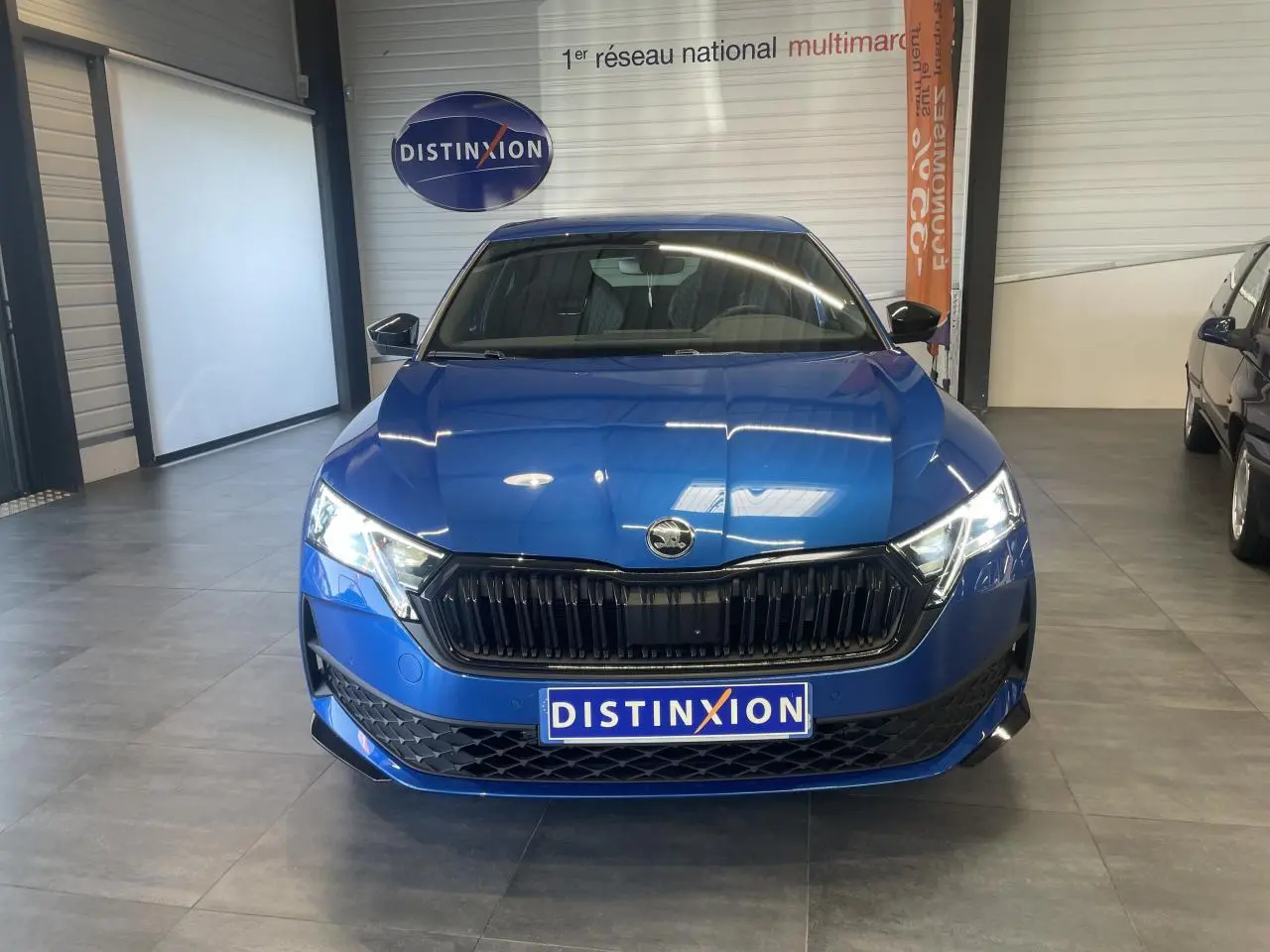 Vue frontale d'une Skoda Octavia Sportline bleu foncé avec calandre noire et phares LED allumés en showroom.