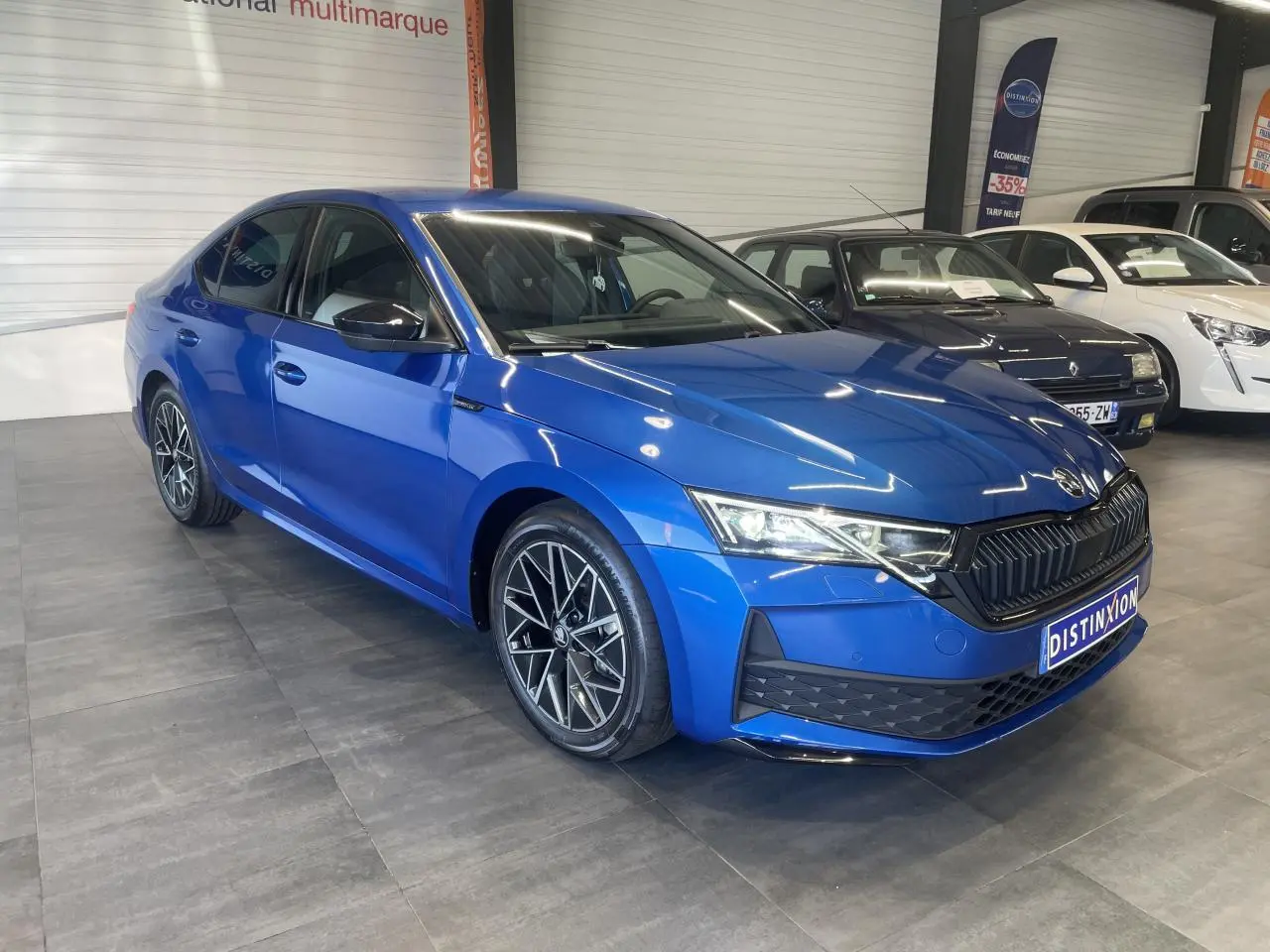 Vue 3/4 avant gauche d'une Skoda Octavia 2025 bleu foncé avec jantes alliage noires et calandre noire sportive.