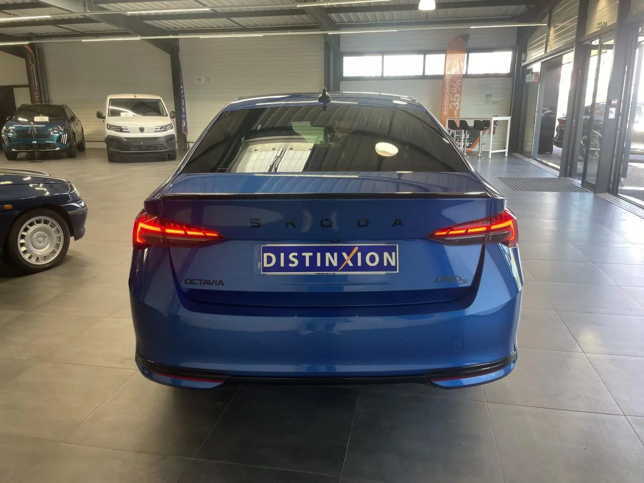 Vue arrière d'une Skoda Octavia bleu foncé avec feux arrière LED allumés dans un showroom.