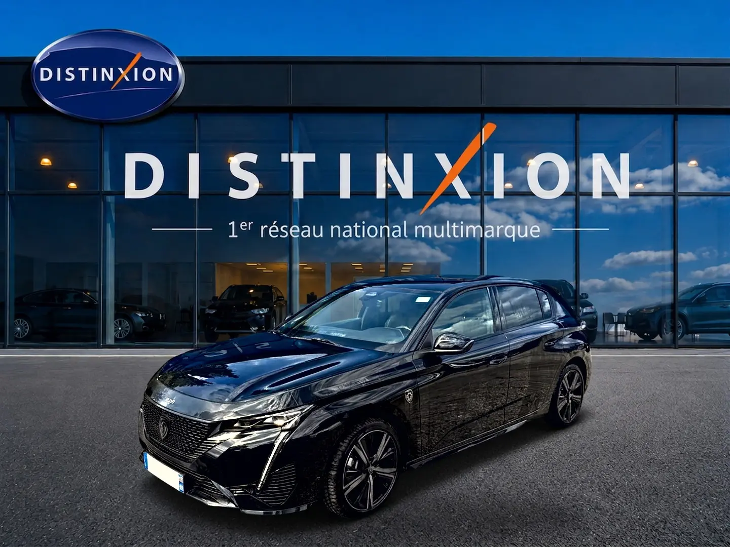 Peugeot 308 1.2 hybrid 145 GT noir vue 3/4 avant, avec jantes alu et calandre distinctive devant un showroom Distinxion.