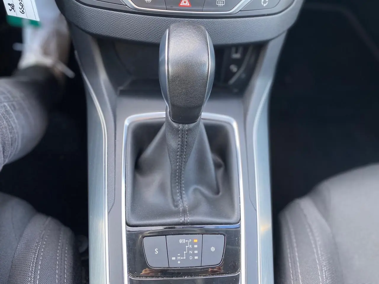 Le levier de vitesse automatique noir de la Peugeot 308 gris aluminium vu de dessus, entouré de la console centrale.