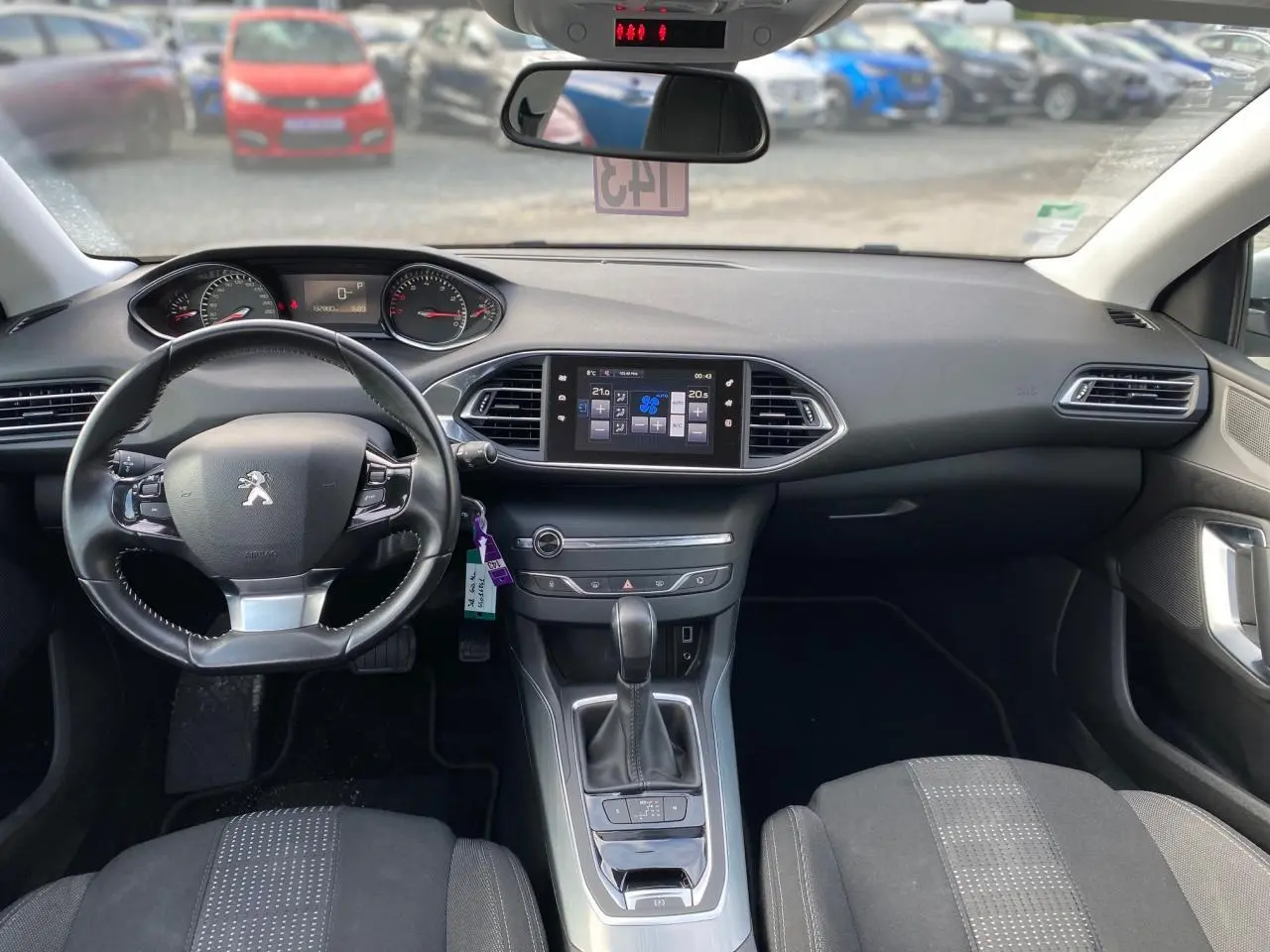 Vue intérieure avant de la Peugeot 308 2016, tableau de bord noir avec volant cuir et écran tactile central.