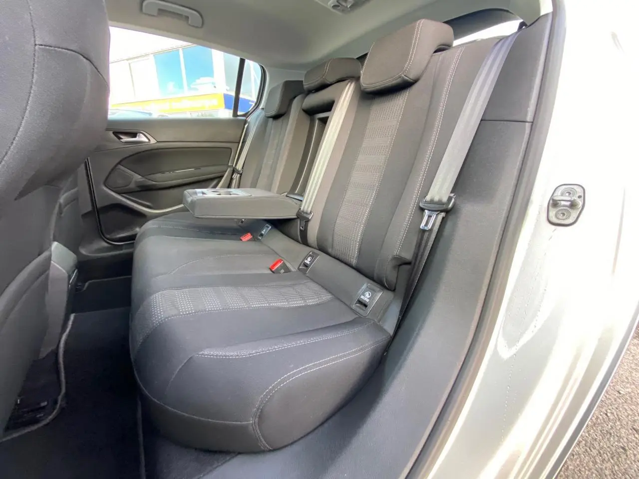 Vue intérieure côté droit des sièges arrière noirs avec accoudoir central relevé d'une Peugeot 308 gris aluminium de 2016.