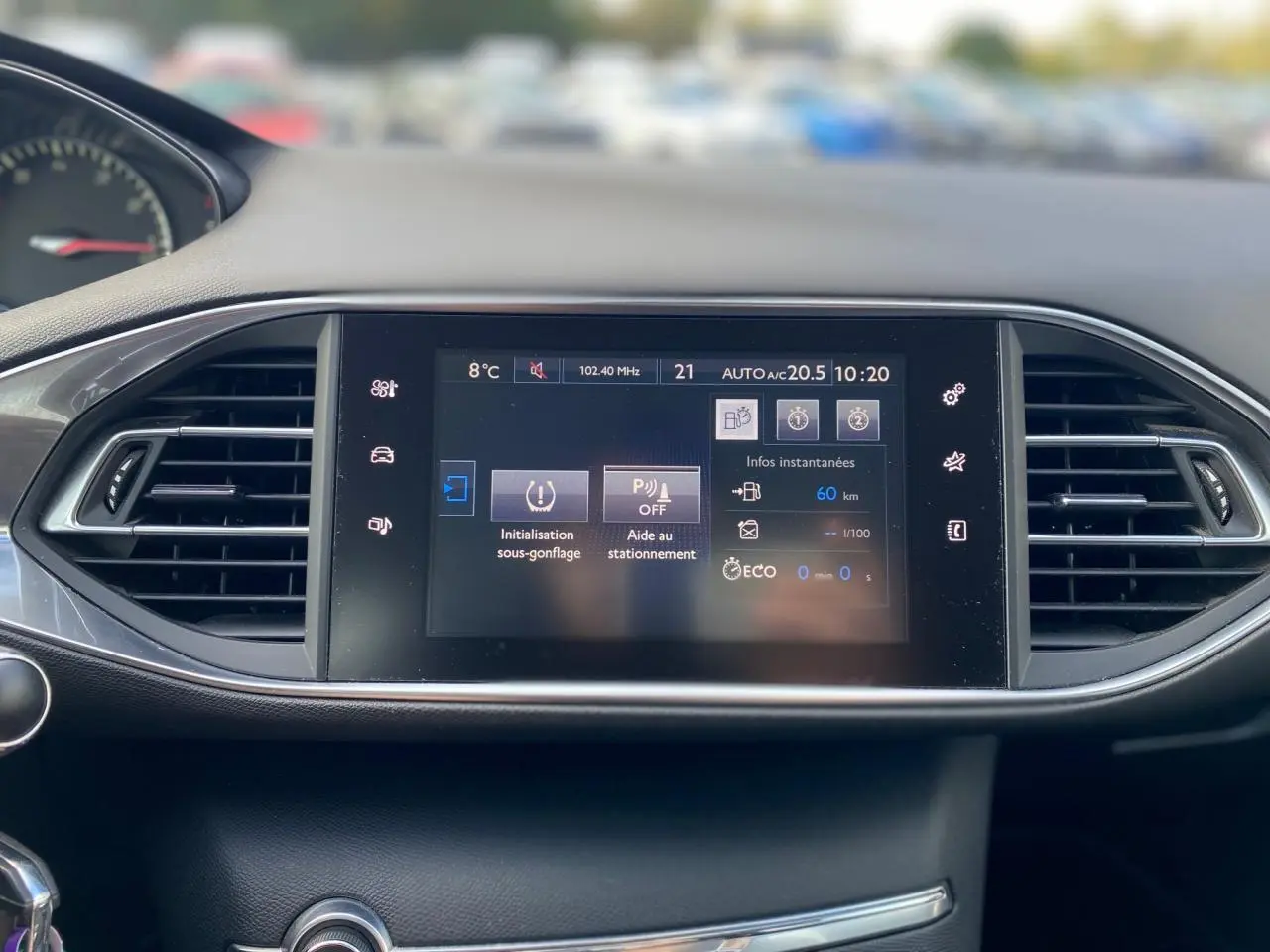 Écran tactile central du tableau de bord de la Peugeot 308 2016 avec affichage des aides au stationnement et température extérieure.
