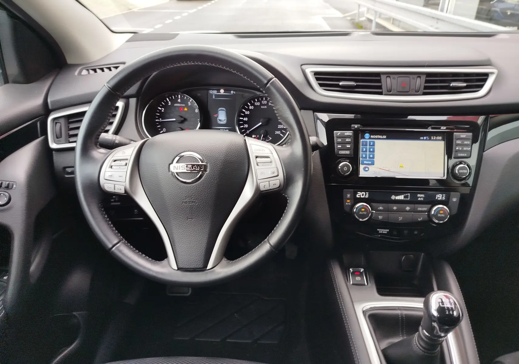 Vue intérieure frontale du tableau de bord du Nissan Qashqai 2017, avec volant cuir noir et console centrale équipée d’un écran tactile.