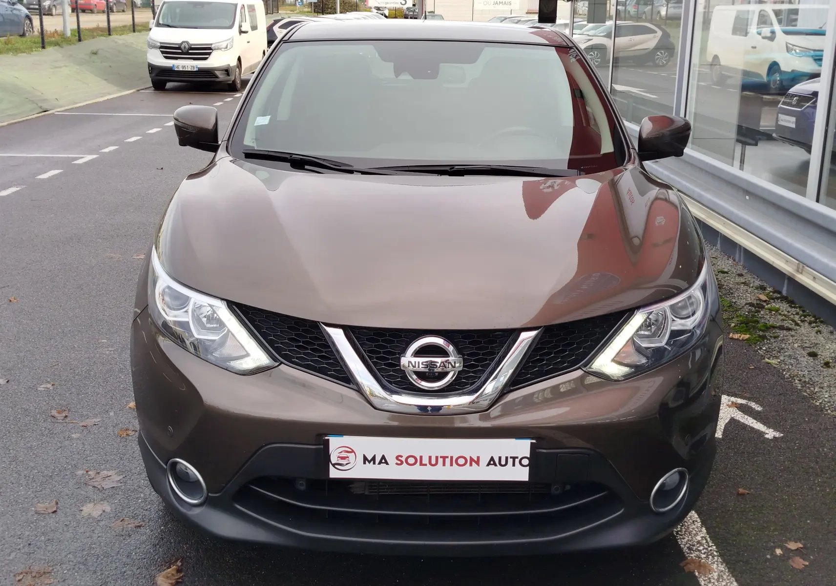 Vue avant d'un Nissan Qashqai bronze Ultime 2017, mettant en valeur sa calandre et ses phares LED allumés.