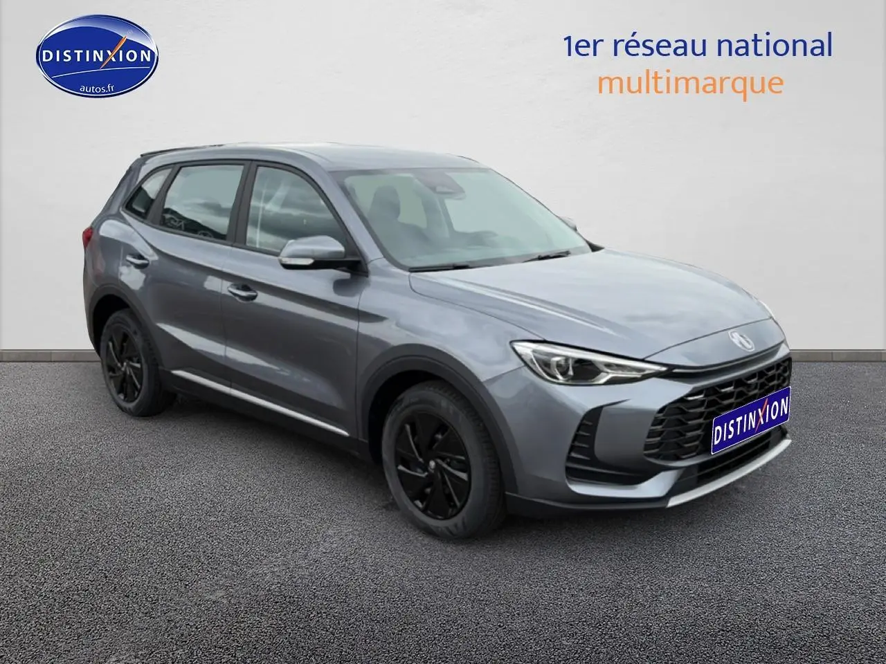 Vue 3/4 avant droit du SUV hybride MG ZS gris avec jantes noires et calandre imposante.