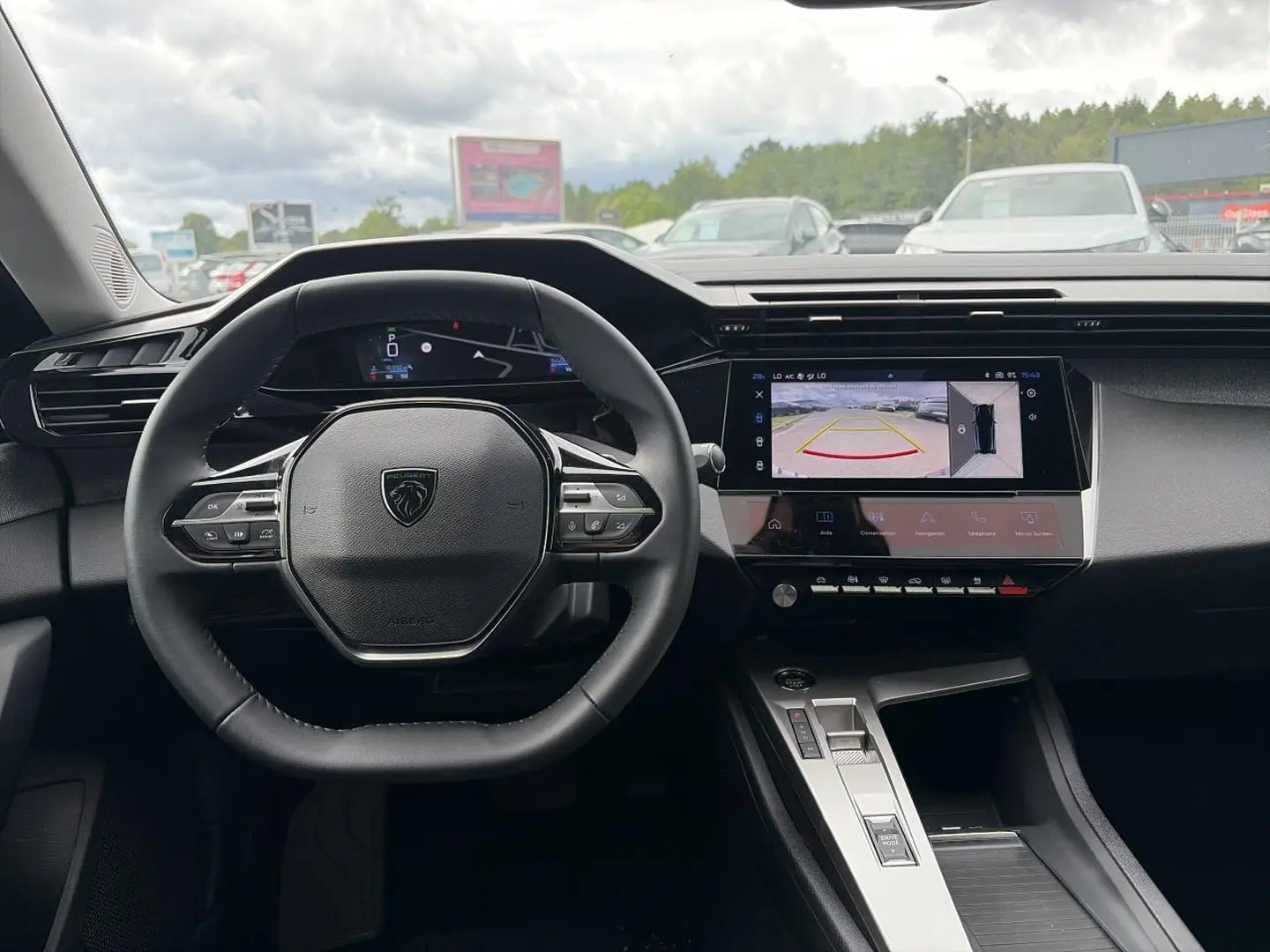 Vue intérieure centrée sur le volant Peugeot 308 gris, avec écran tactile affichant la caméra de recul.