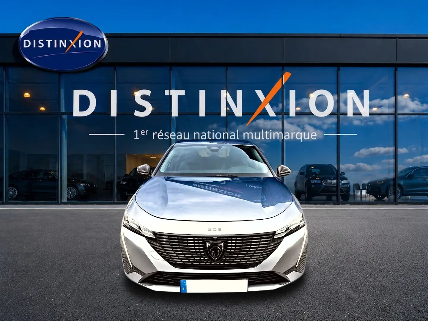 Vue avant d'une Peugeot 308 gris artense avec calandre noire et logo lion, devant une vitrine Distinxion.