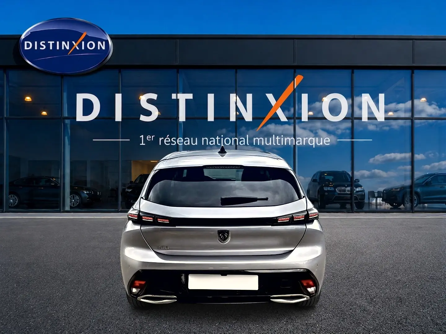 Vue arrière d'une Peugeot 308 gris artense garée devant une vitrine avec logo Distinxion.