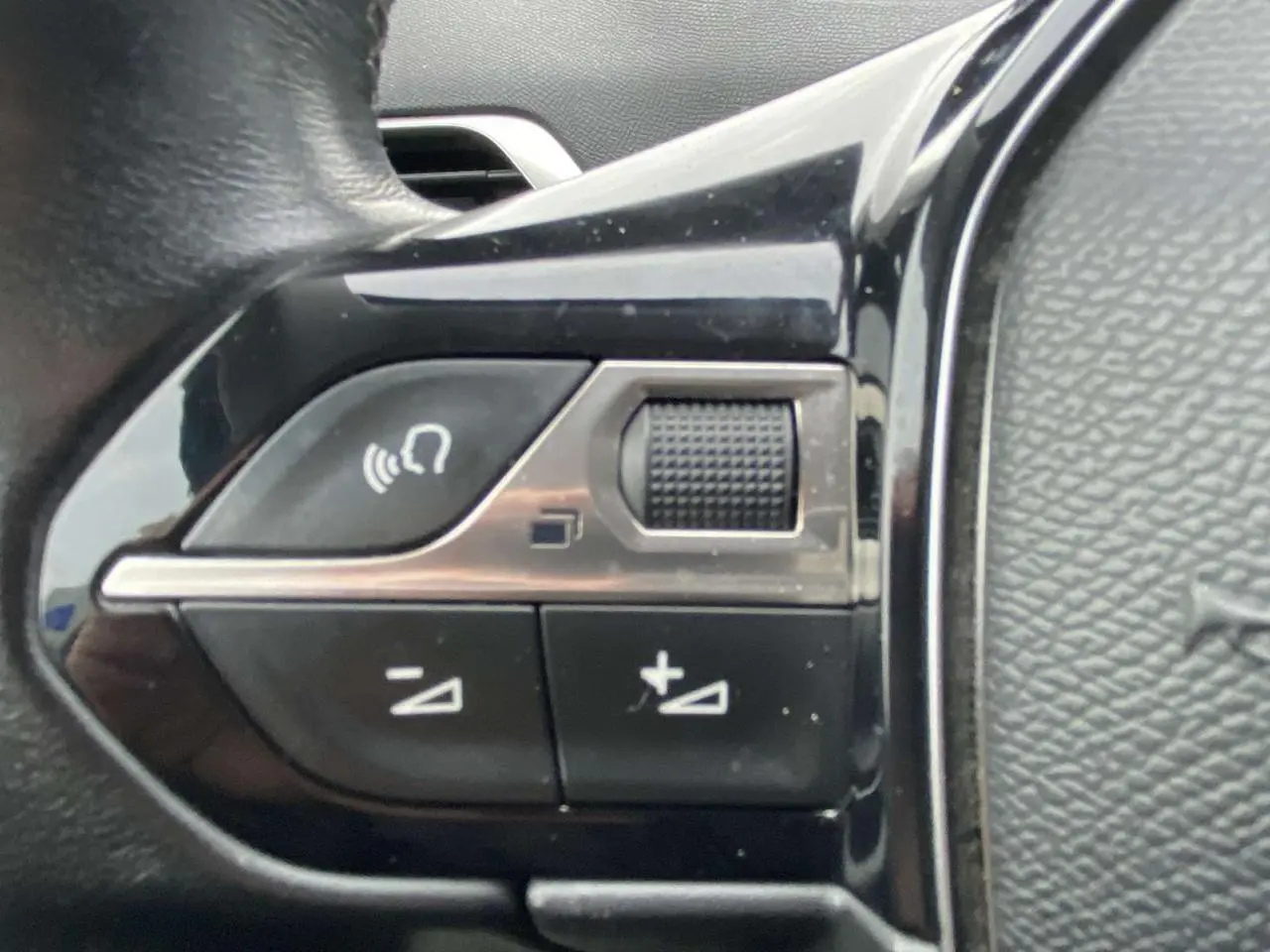 Gros plan sur les commandes de volume au volant du Peugeot 3008 marron foncé de 2017.