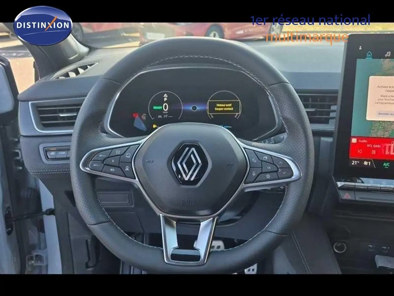 Vue rapprochée du volant multifonction noir avec logo Renault et tableau de bord numérique du Captur E-Tech hybride.