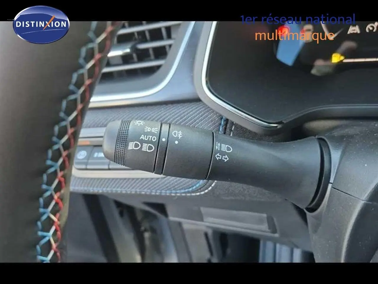 Gros plan sur la commande des feux à gauche du volant du Renault Captur gris rafale, intérieur avec surpiqûres colorées.