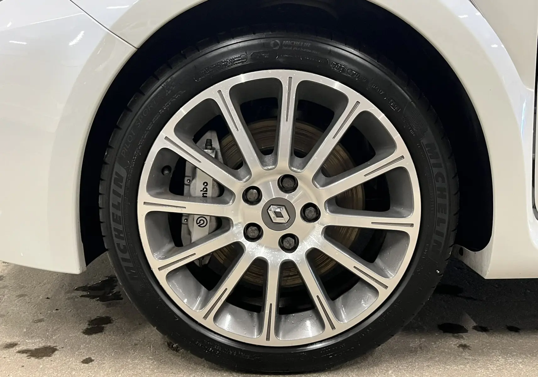 Gros plan sur la jante alliage 17 pouces et le frein Brembo de la Renault Clio III RS 20th Anniversary blanc nacré.