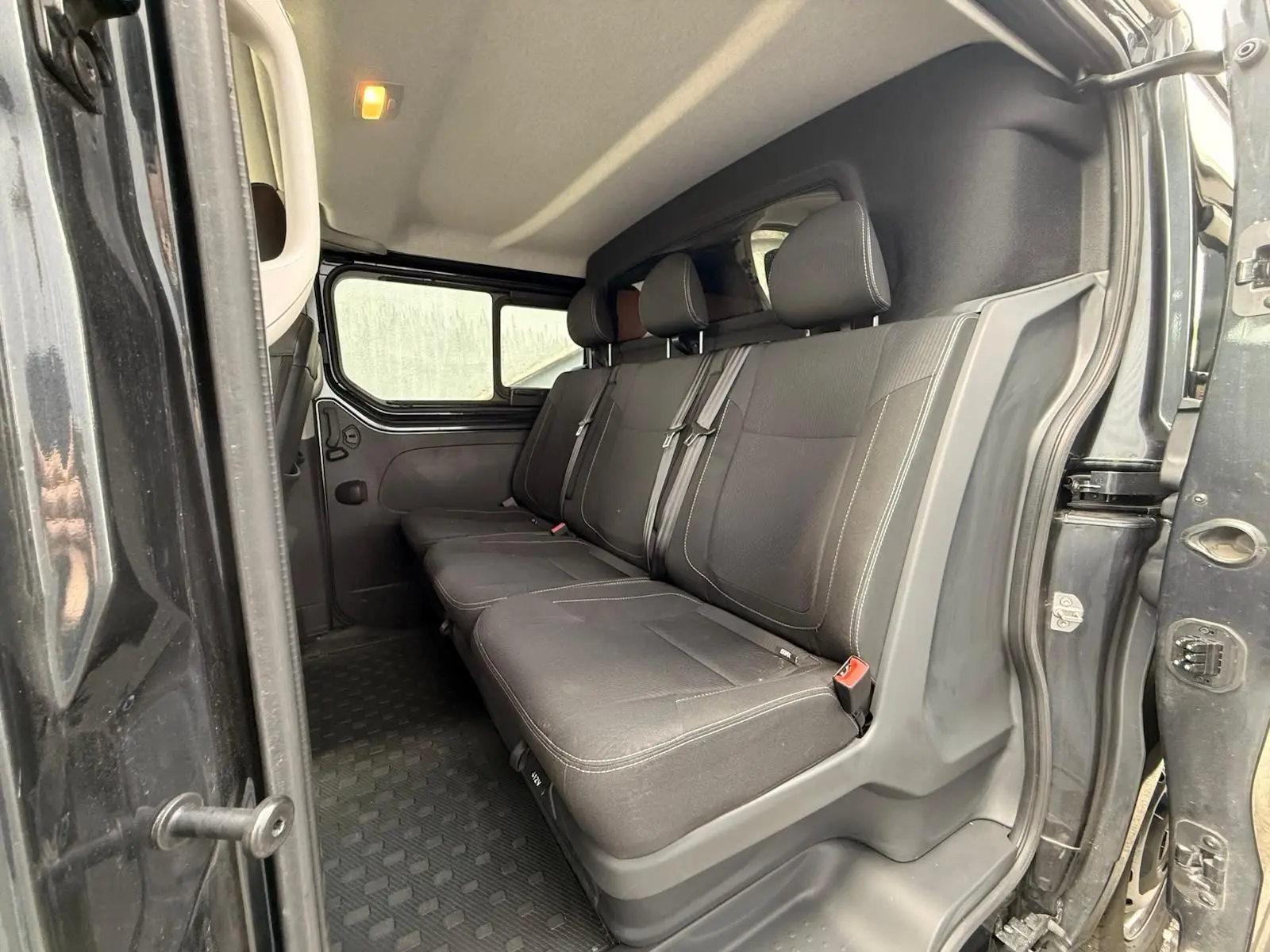 Vue intérieure côté droit montrant la banquette arrière noire du Renault Trafic Cabine Approfondie gris comète.