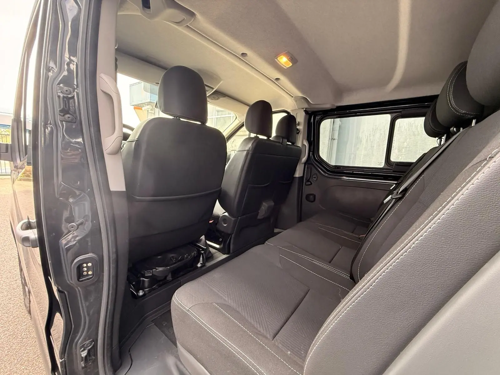 Vue intérieure côté droit du Renault Trafic Cabine Approfondie gris comète, montrant les sièges arrière et avant en tissu noir.
