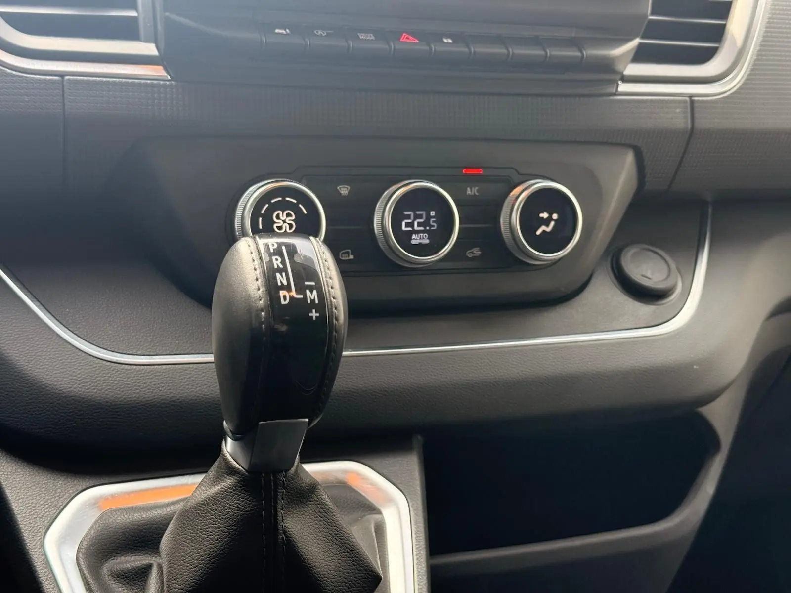 Gros plan sur la commande de boîte automatique et les réglages climatiques du tableau de bord du Renault Trafic gris.