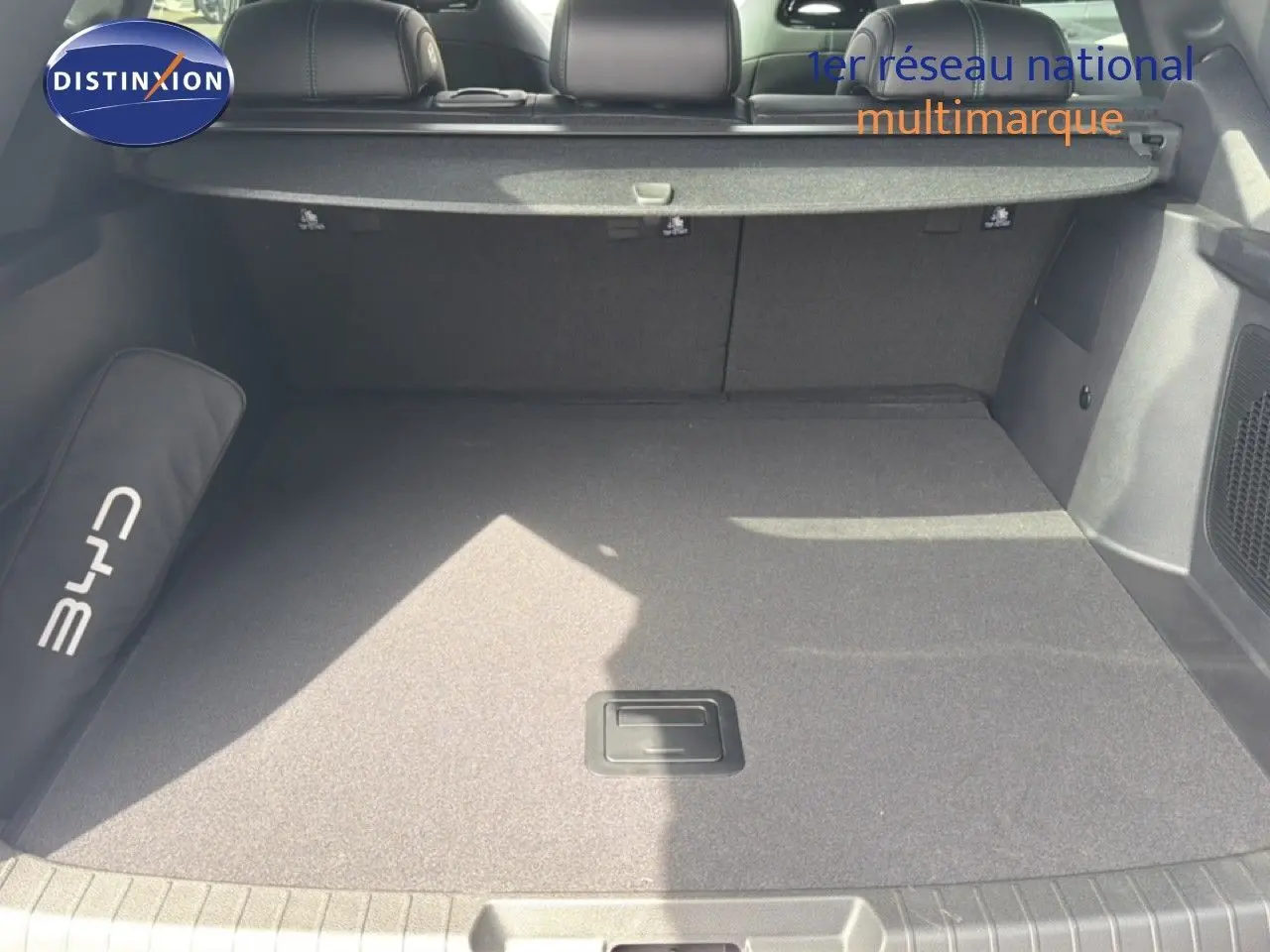Coffre spacieux vu de l'arrière d'un BYD SEAL U blanc métal, avec tapis gris et cache-bagages déployé.