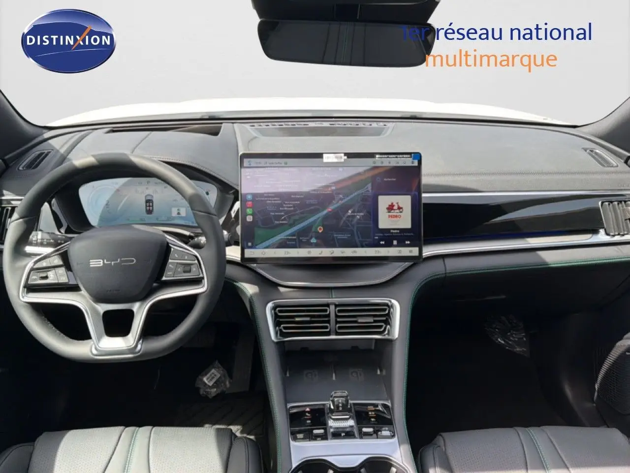Vue intérieure avant du tableau de bord et volant du BYD SEAL U blanc métal, avec écran tactile central et finitions modernes.