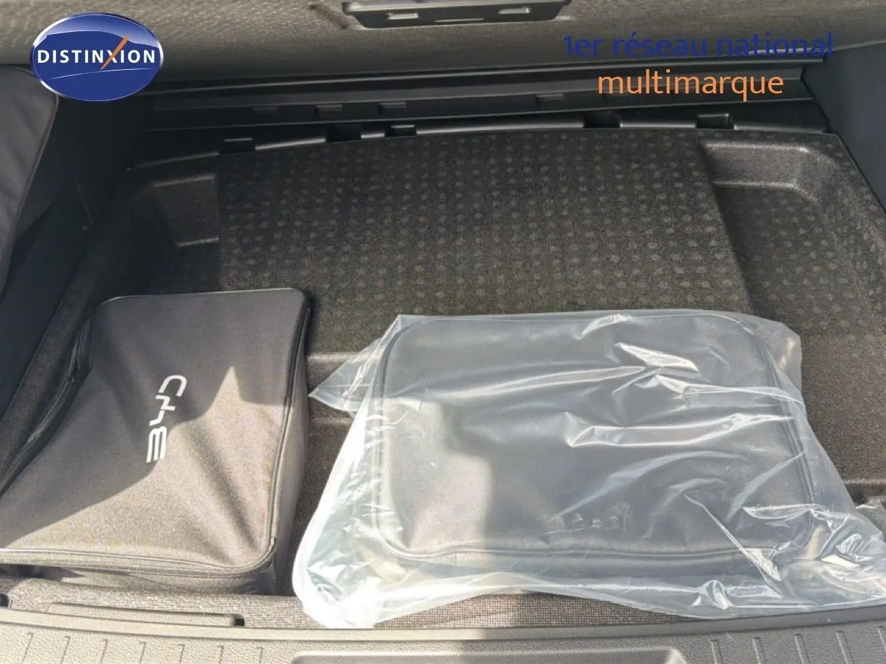 Coffre ouvert du BYD SEAL U blanc métal 2026 montrant deux sacs de rangement, dont un sous plastique transparent.